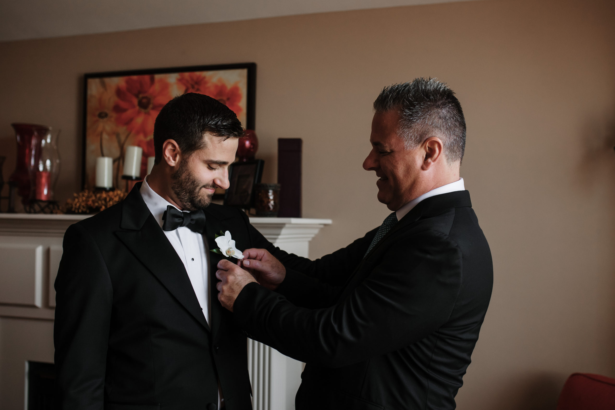father of the groom is helping dress groom