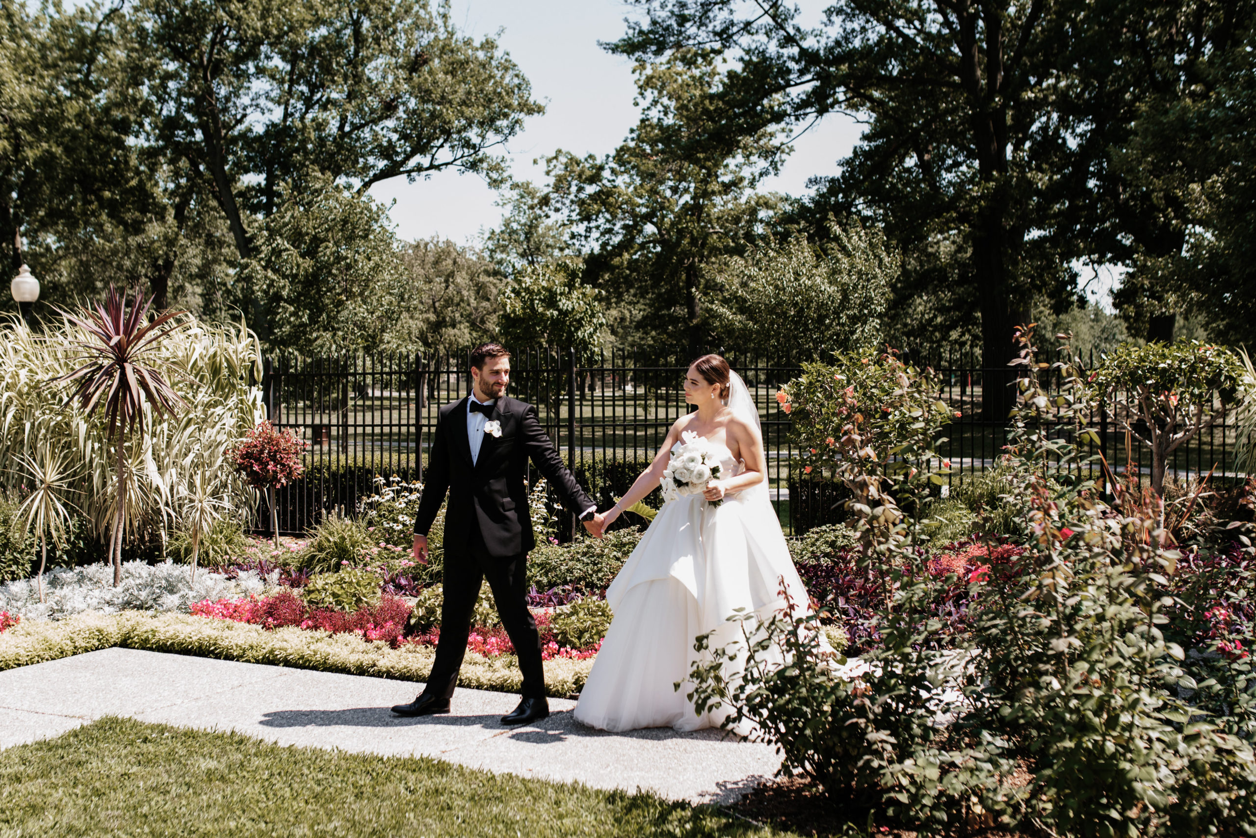 Bride and groom walking in the  lush gardens of Willistead Manor